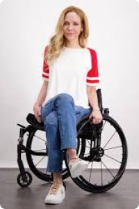 Woman in a wheelchair crossed legged wears jeans and a raglan white and red top